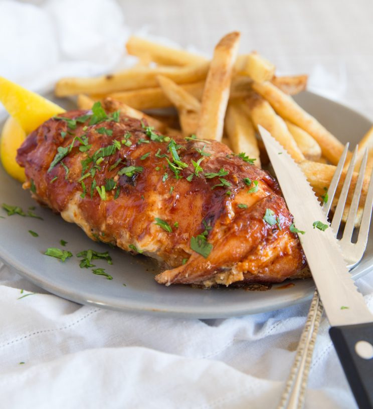 Triple Cheese Stuffed Chicken Wrapped in Bacon with chips and lemon wedges