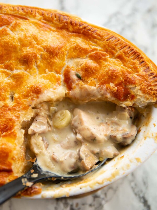 close up shot of black serving spoon digging into chicken leek mushrooms pie