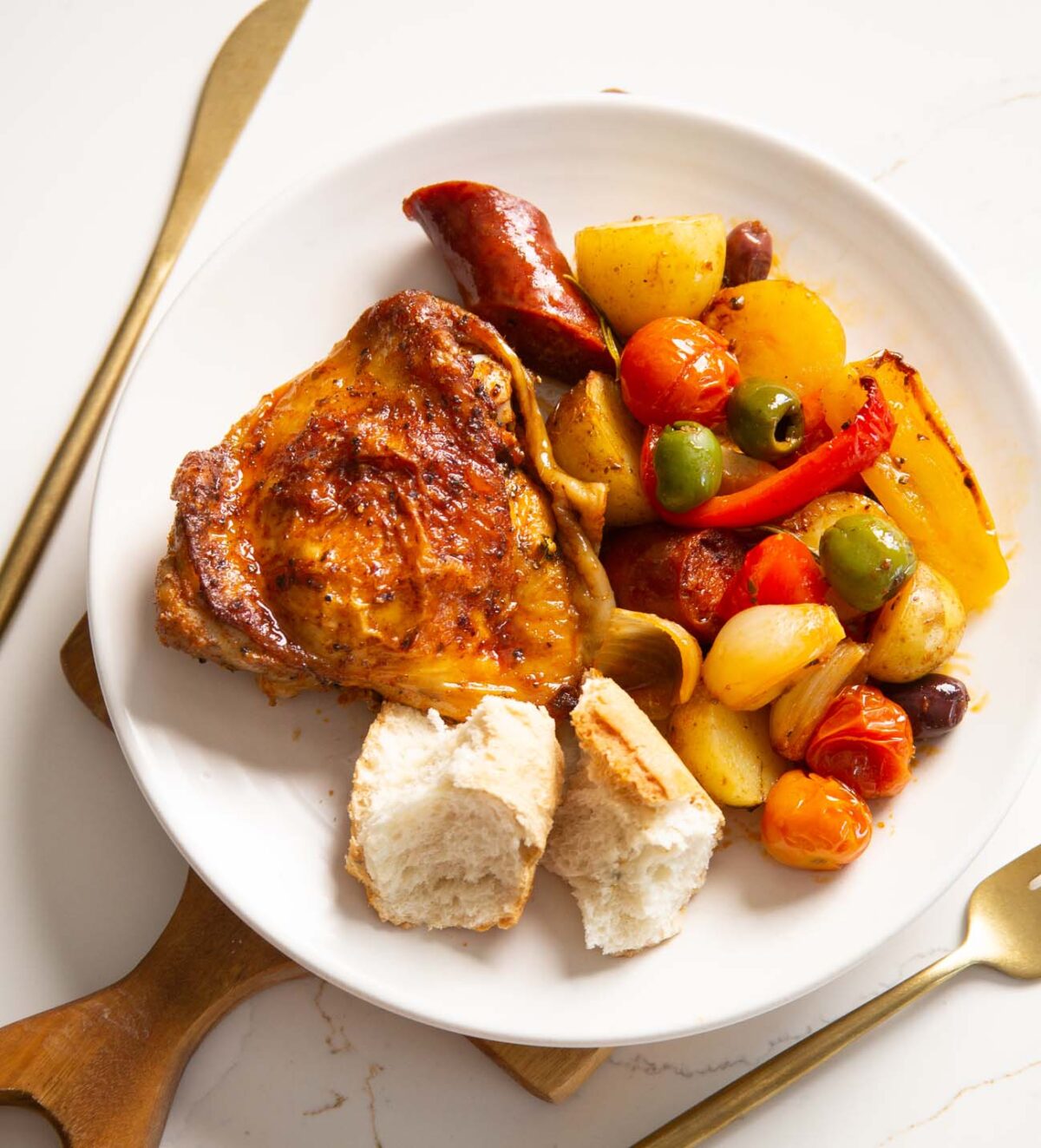 spanish chicken traybake served on small white plate with gold cutlery