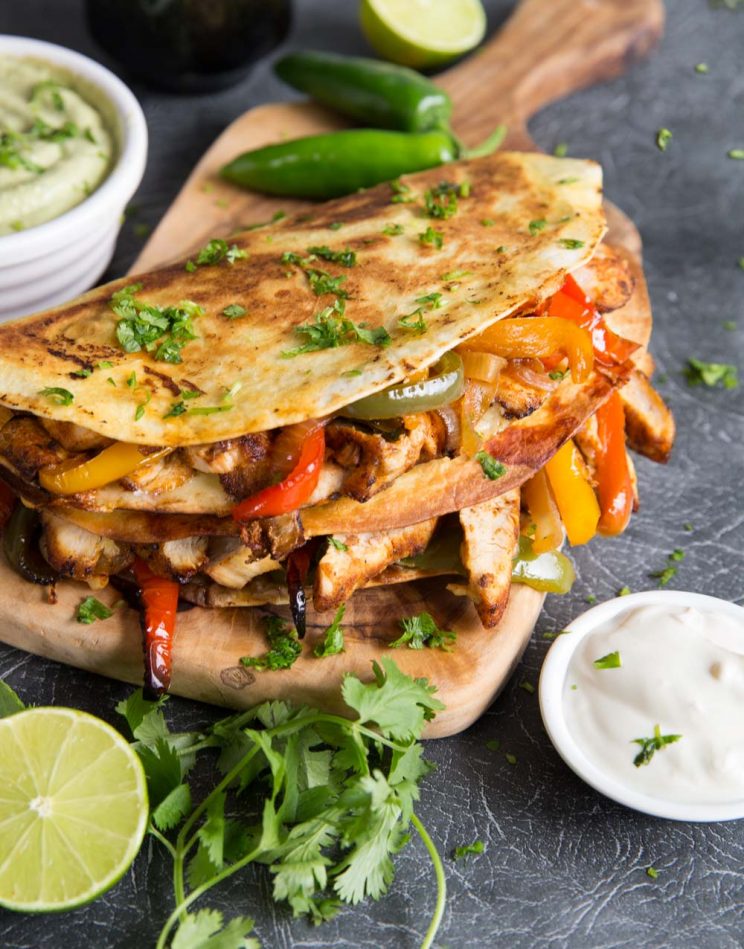 quesadillas on chopping board garnished with coriander served with sour cream