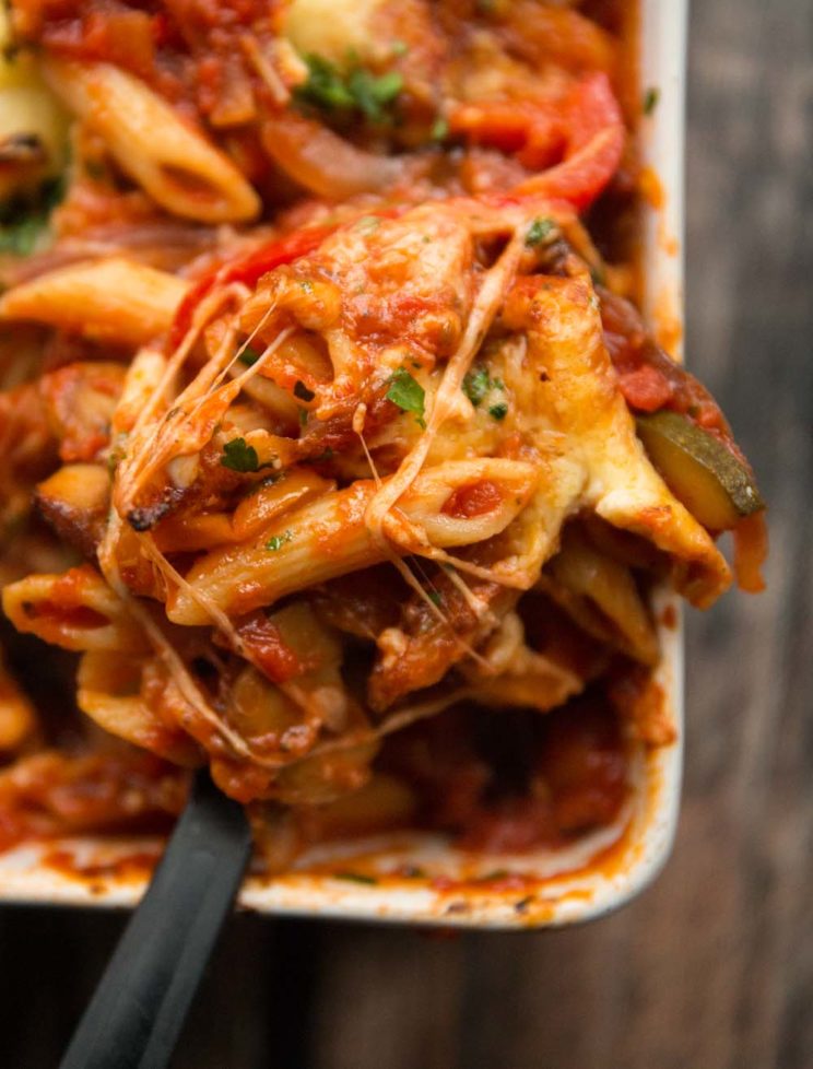 overhead closeup shot of pasta bake being scooped out of baking dish