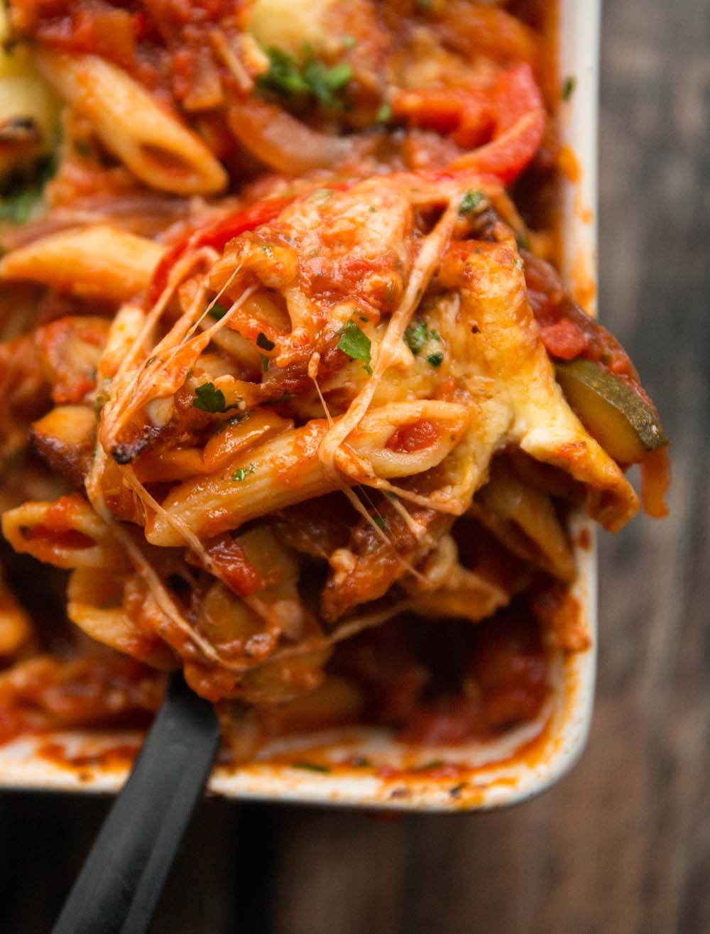 overhead closeup shot of pasta bake being scooped out of baking dish