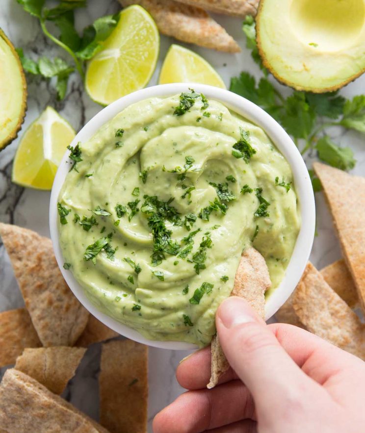 overhead shot of Avocado Dip with pita bread chips dunking in