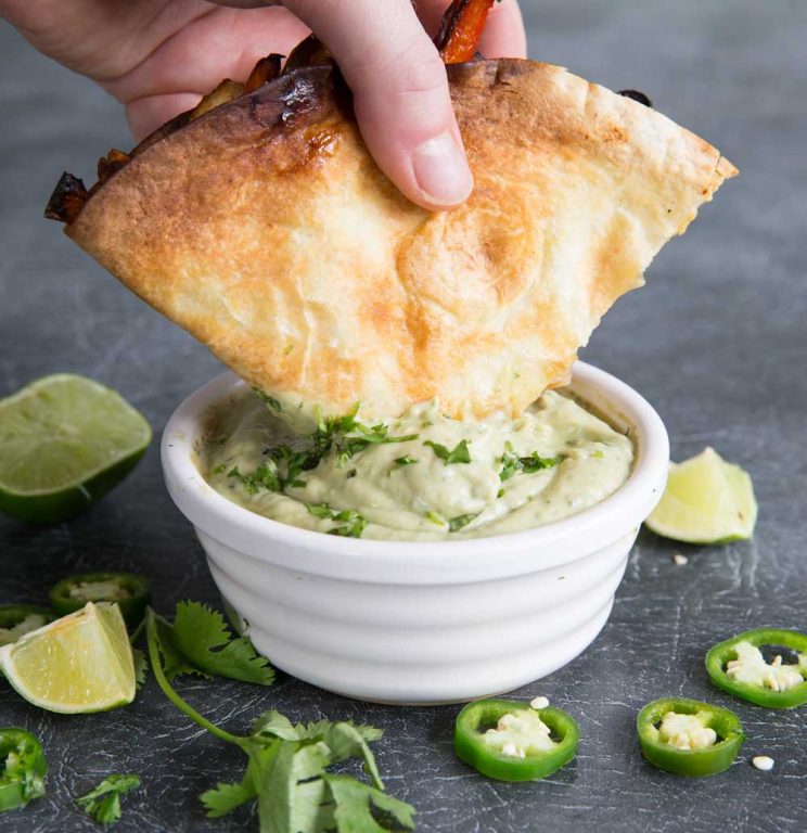 Chicken quesadilla and avocado dip surrounded by jalapenos