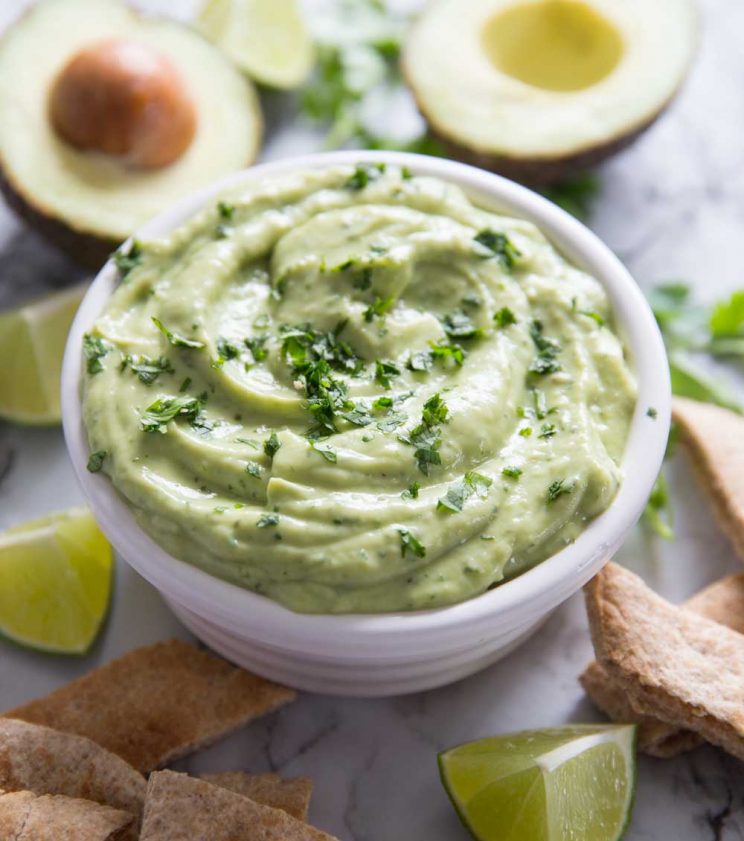 Avocado dip with lime wedges and pita bread