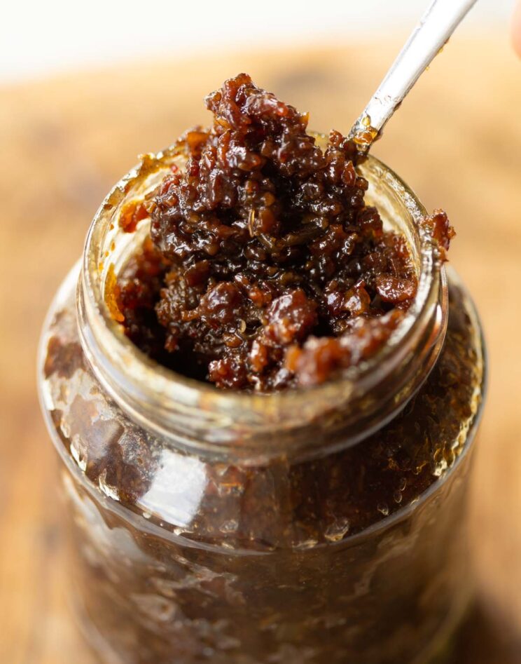 close up shot of homemade bacon jam in glass jar with small silver spoon digging in