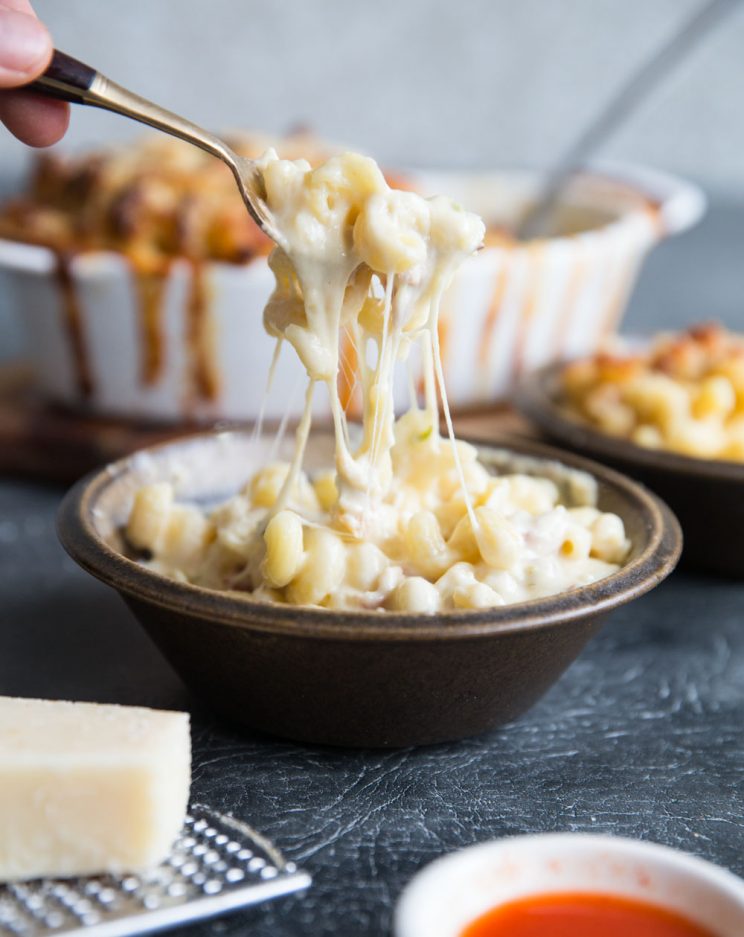 Spicy mac and cheese with bacon in a bowl with cheese pull