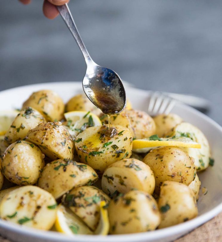Pouring lemon browned butter over boiled baby potatoes