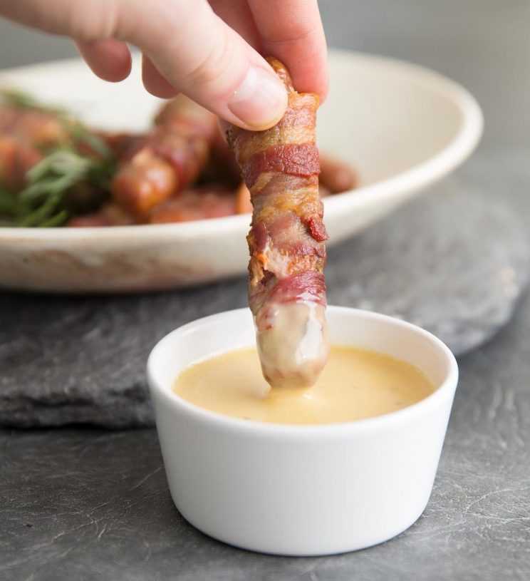 pigs in blanket dipping into honey mustard sauce