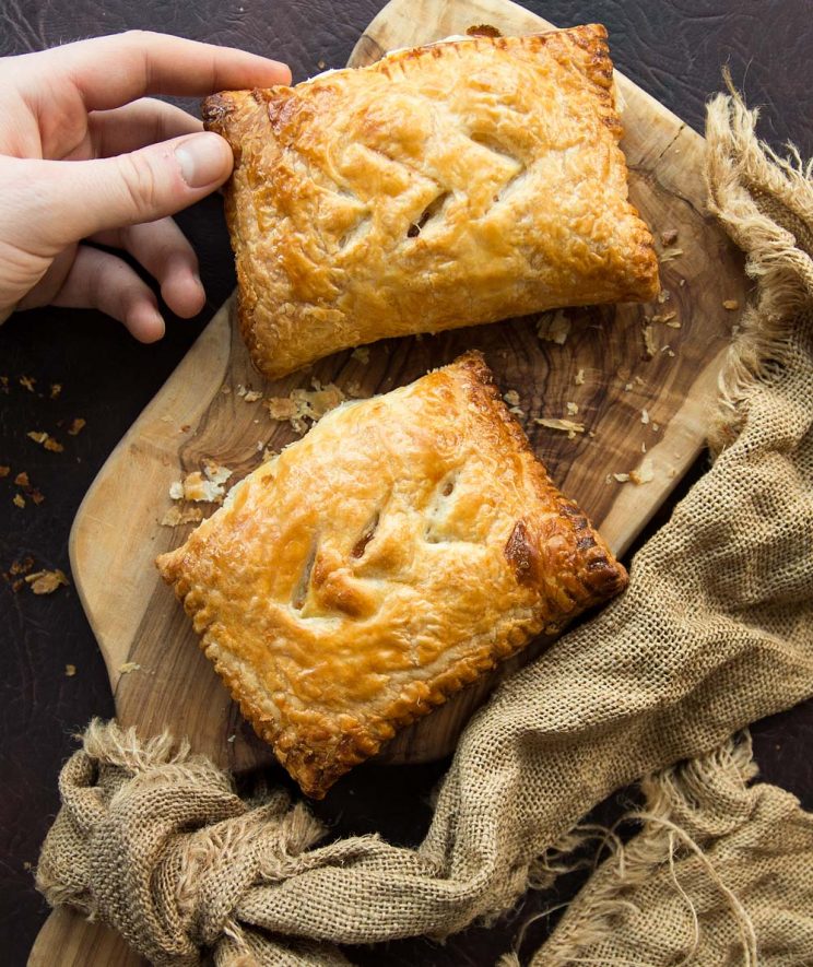 2 homemade cheese and onion pasties fresh out the oven on wooden chopping board