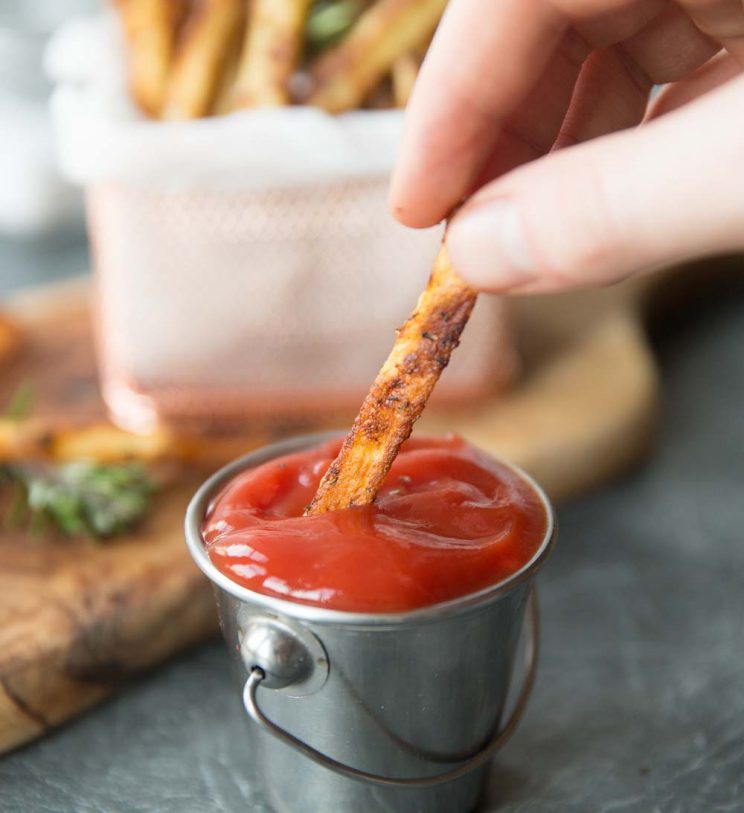 French fries dipping into ketchup