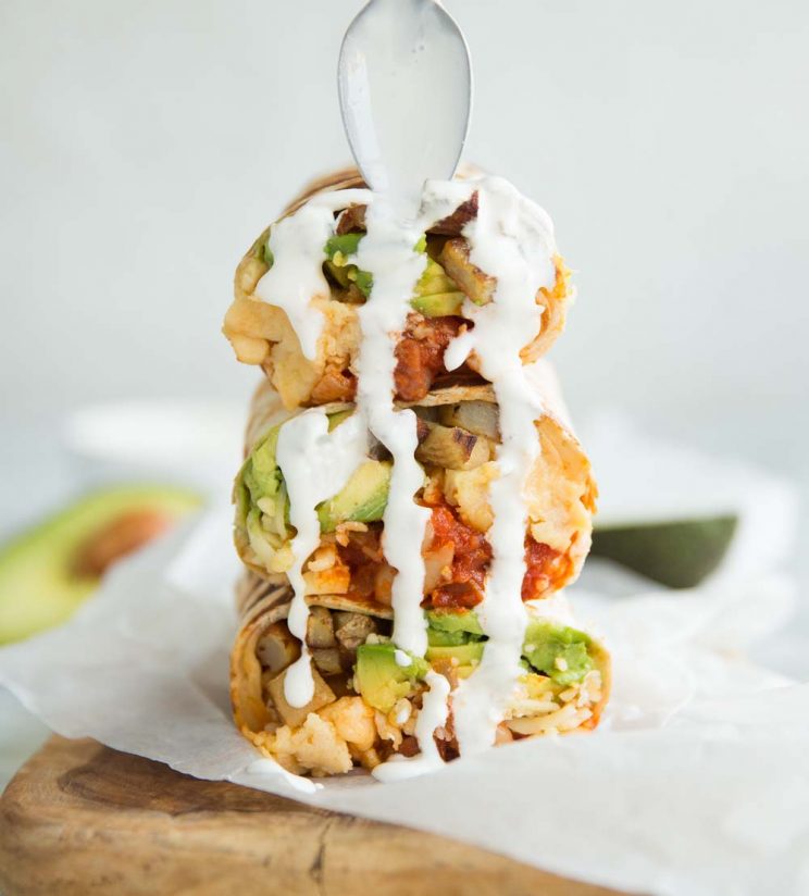 Breakfast Burrito with sour cream pouring down it from a spoon
