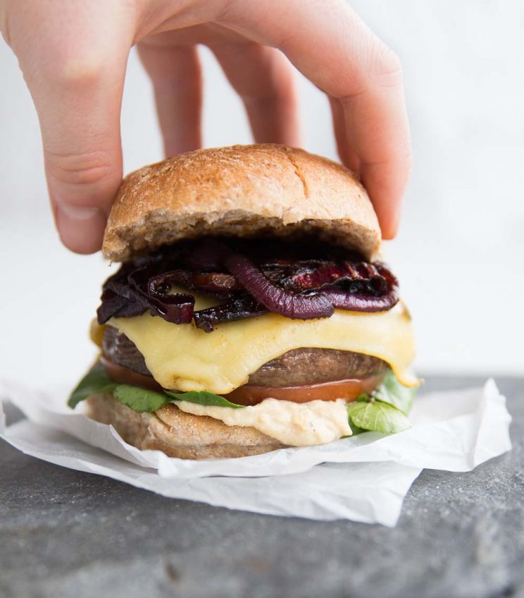 Placing top bun on top of grilled portobello mushroom burger