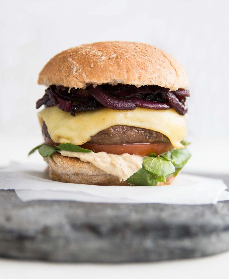 close up shot of Portobello Mushroom Burger with caramelised onions, cheese, hummus, tomato and watercress