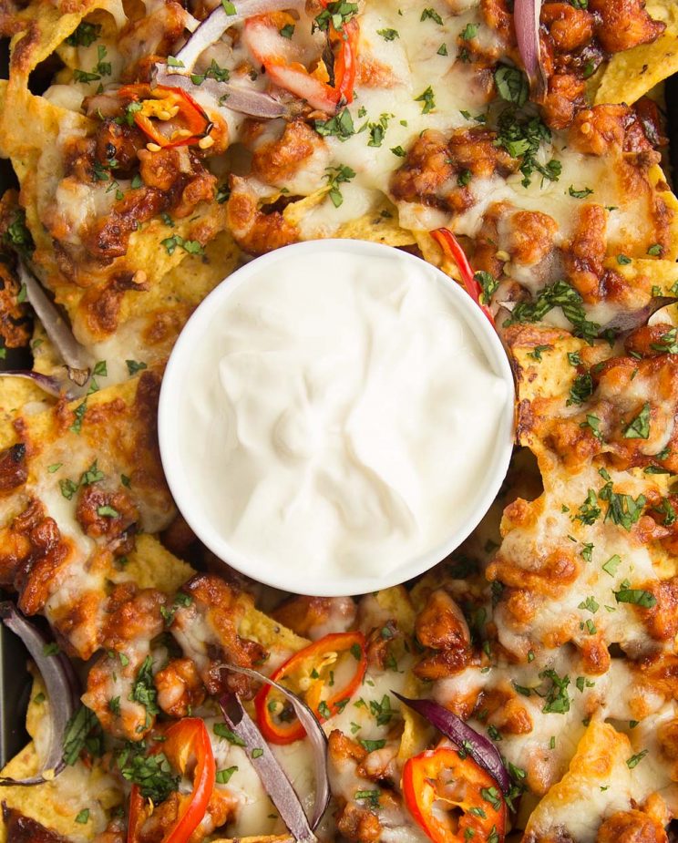 overhead shot of BBQ Chicken Nachos on a tray with sour cream in the middle