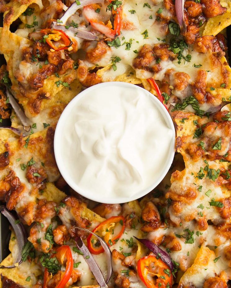 overhead shot of BBQ Chicken Nachos on a tray with sour cream in the middle