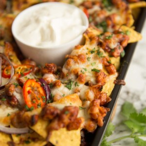 BBq chicken nachos fresh out the oven served with pot of sour cream on the centre