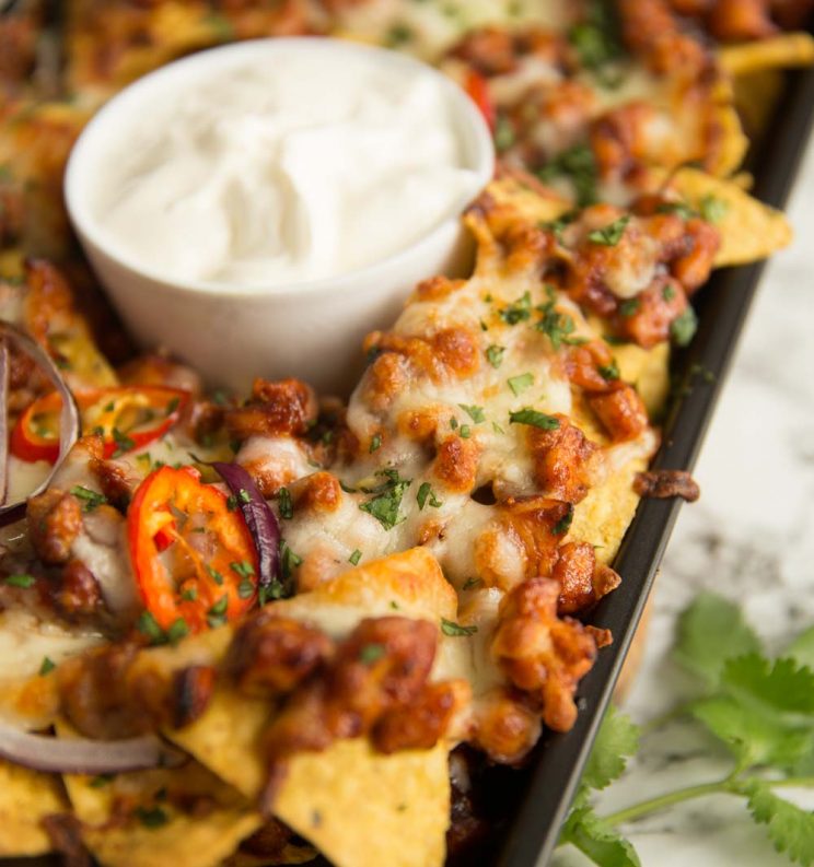 BBq chicken nachos fresh out the oven served with pot of sour cream on the centre