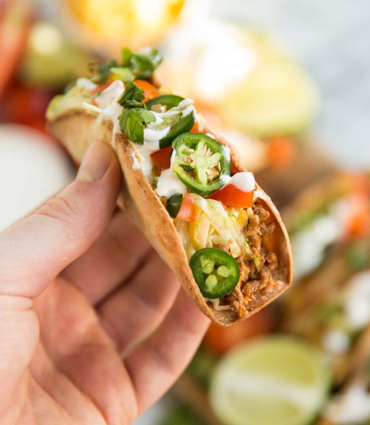 Holding a Spicy Ground Beef Tacos with several other blurred in the background