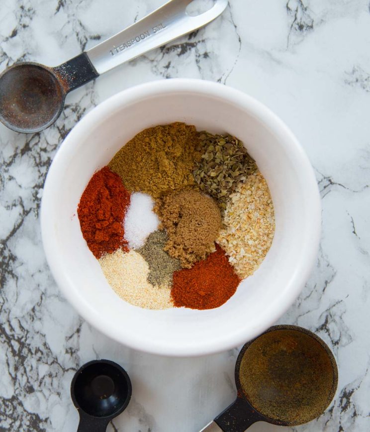 Small bowl with taco seasoning surrounded by measuring spoons