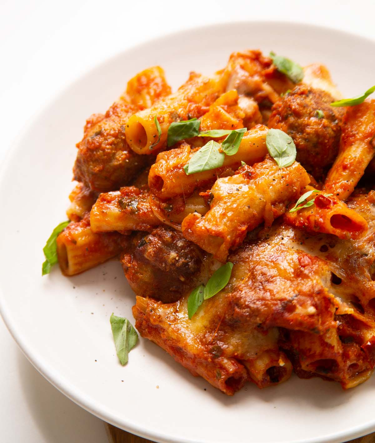 close up shot of meatball pasta bake on small white plate