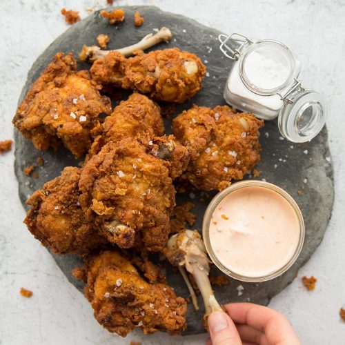 Crispy Buttermilk Fried Chicken on a grey slate with dip and salt