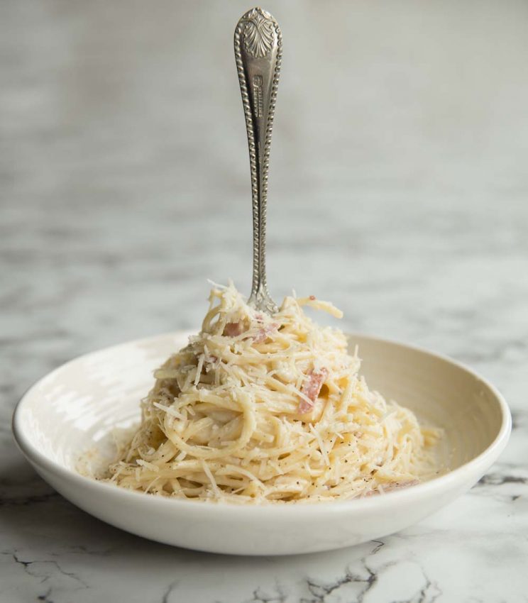 Cream Cheese Pasta in a white bowl with a silver fork sticking out the top