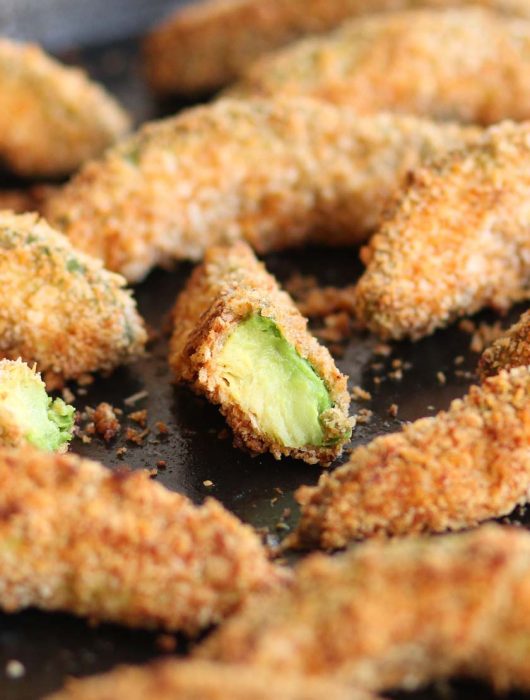 Avocado Fries fresh out the oven with focus on half a fry showing the avocado