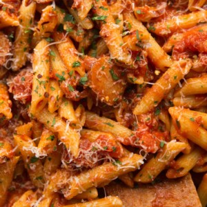 Overhead shot of Arrabiata in a saucepan garnished with parmesan, chilli flakes and parsley