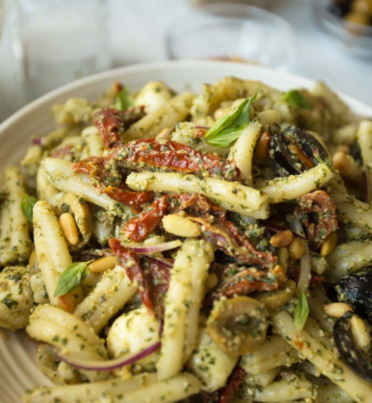 Close up shot of pesto pasta salad with focus on sun dried tomato