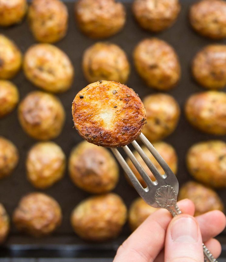 overhead shot of the crispy bottom half of a baby potato with a full tray blurred in the background