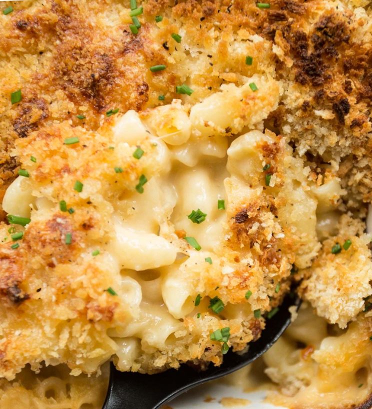 Baked mac and cheese fresh out the oven with a spoon breaking through the breadcrumbs