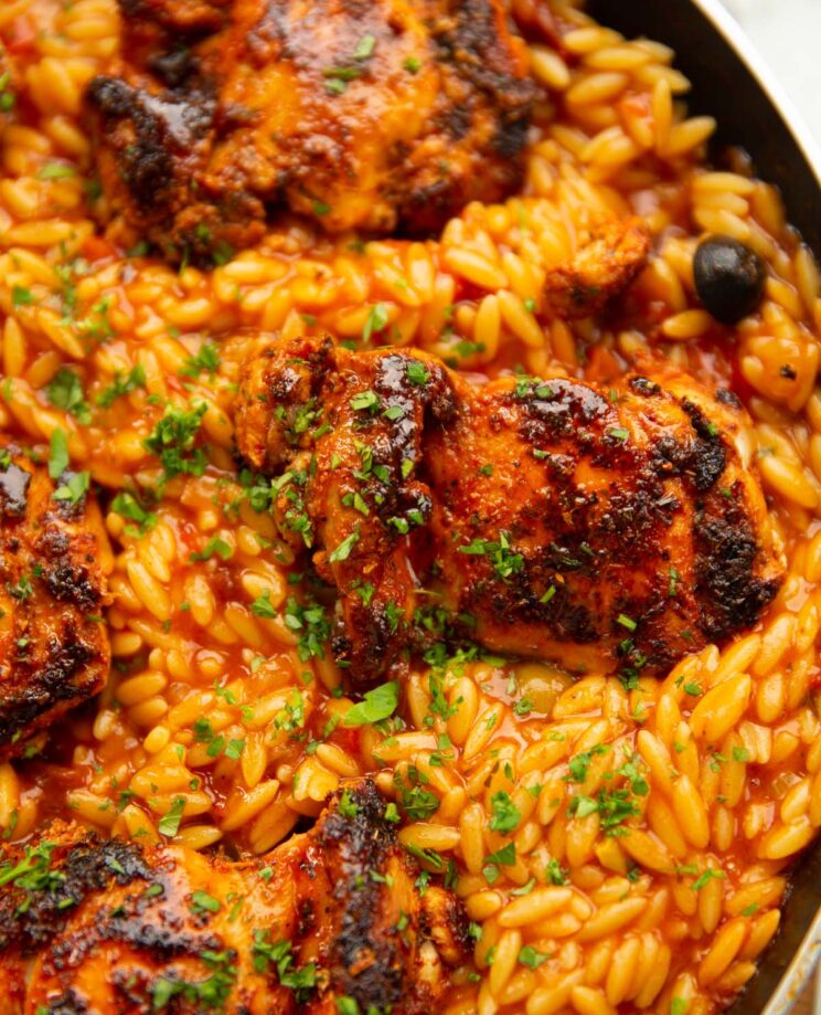 close up shot of spanish chicken with orzo garnished with parsley