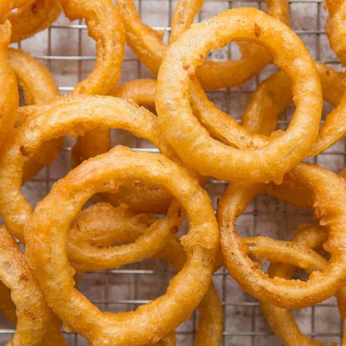 overhead shot of onion rings scattered across a wire rack