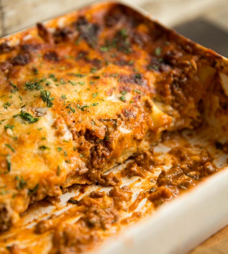 half of a lasagne in the baking dish with ragu spilling out