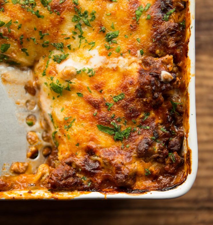 overhead shot of lasagne in baking dish fresh out the oven with spatula digging into it