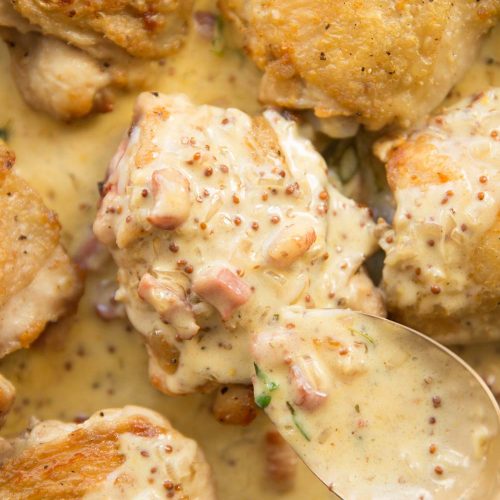 over shot of pouring creamy sauce over chicken thighs in a skillet
