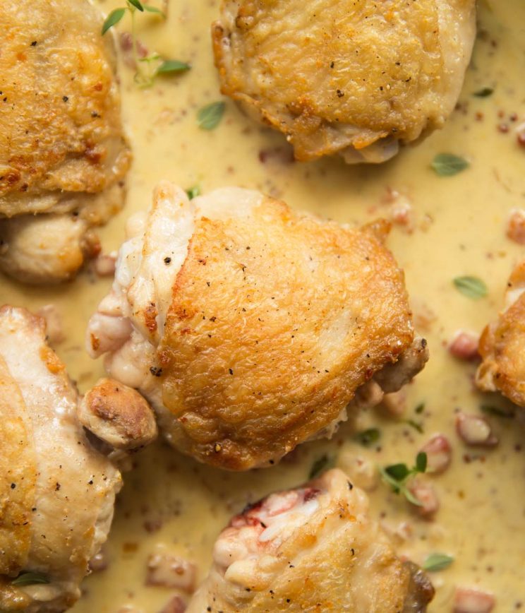 overhead shot of crispy chicken thighs in a skillet of creamy honey mustard sauce
