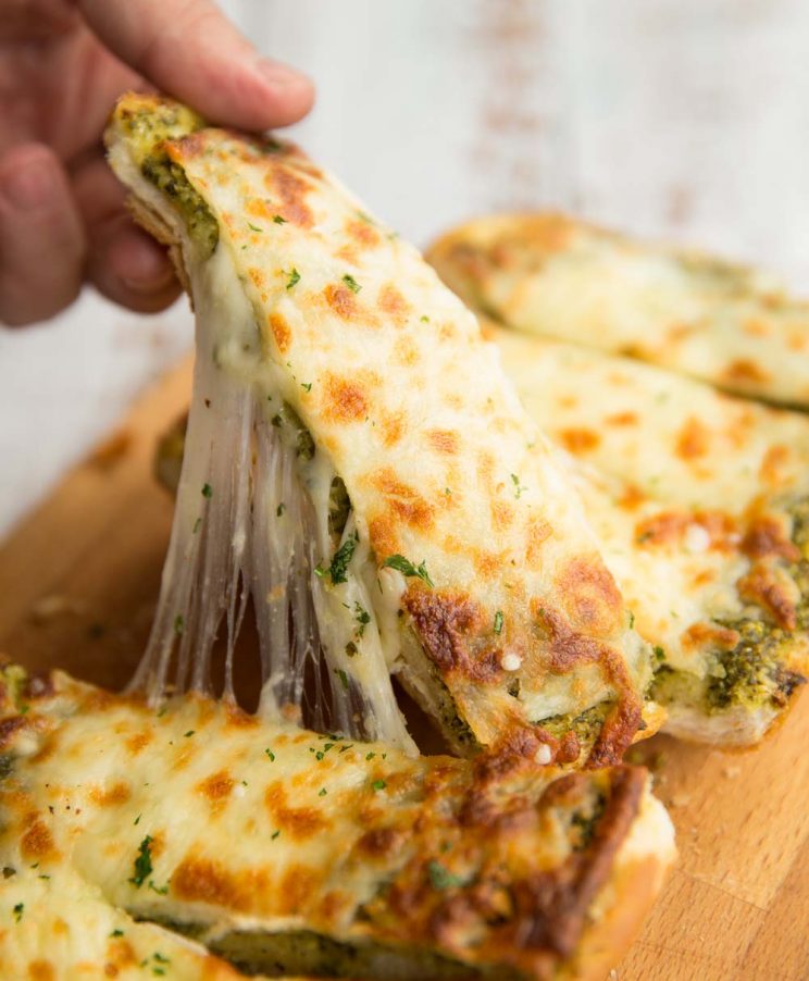 Pull one slice of garlic bread away from loaf with cheese pulling away