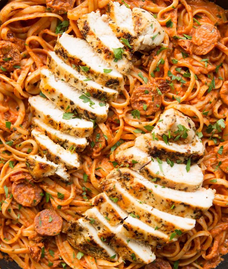 overhead shot of chorizo pasta and sliced grilled chicken on top in pan