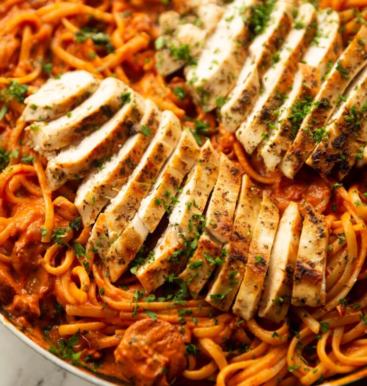 close up shot of chorizo chicken pasta in pan focus on sliced chicken