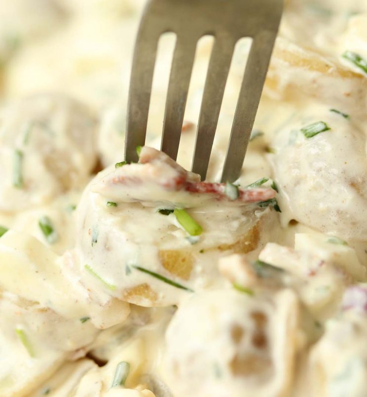 closeup shot of fork cutting into potato and bacon