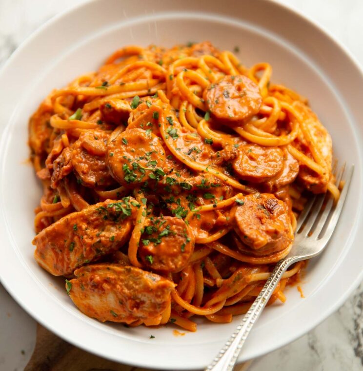 close up shot of chorizo chicken pasta in white bowl with silver fork digging in
