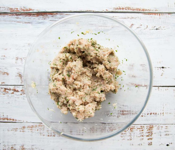 overhead shot of chicken mince and seasoning in a glass bowl