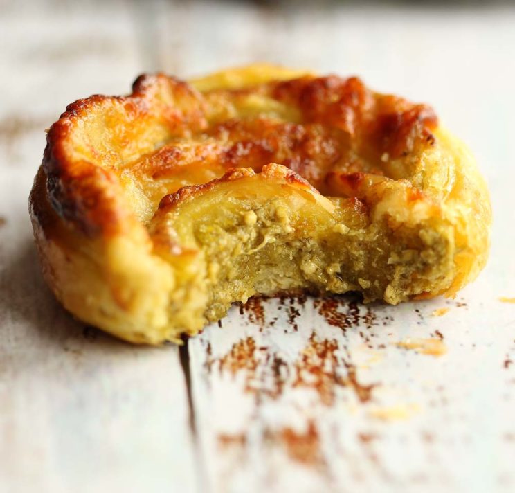 side shot of pesto puff pastry pinwheel with bite taken out of it