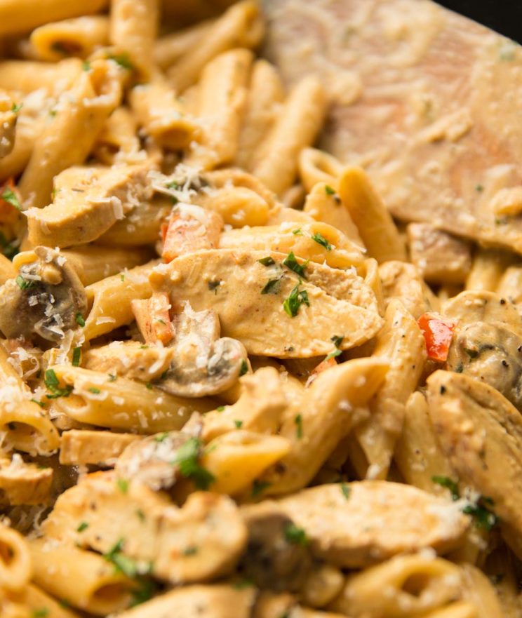 cajun chicken pasta in a skillet with wooden spoon blurred in background
