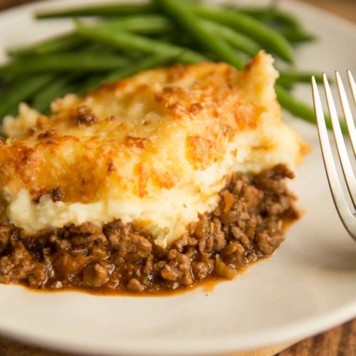 shepherd's pie plated up with green beans blurred in the background