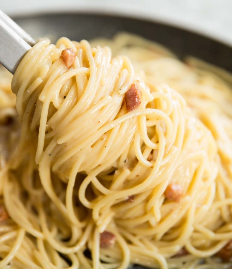 twisting carbonara in a saucepan with pasta tongs