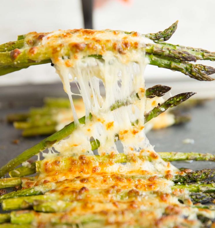 pulling cheesy asparagus off tray with spatula