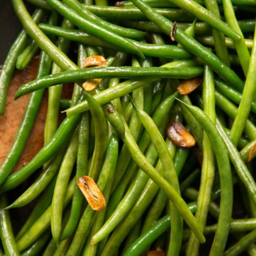 overhead shot of green beans in pan with crispy bits of garlic